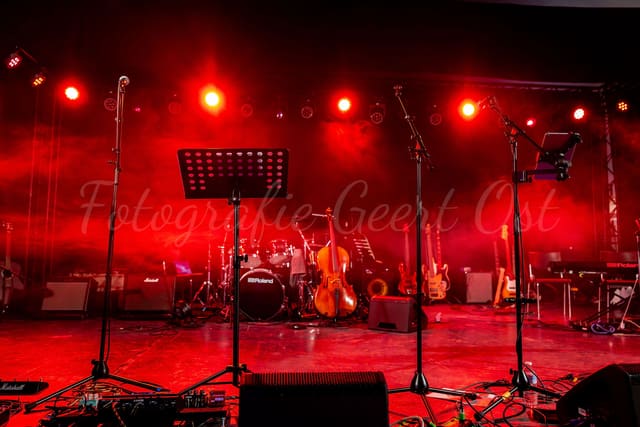 Leeg podium in rood licht met klaargezette instrumenten, micro's en monitors