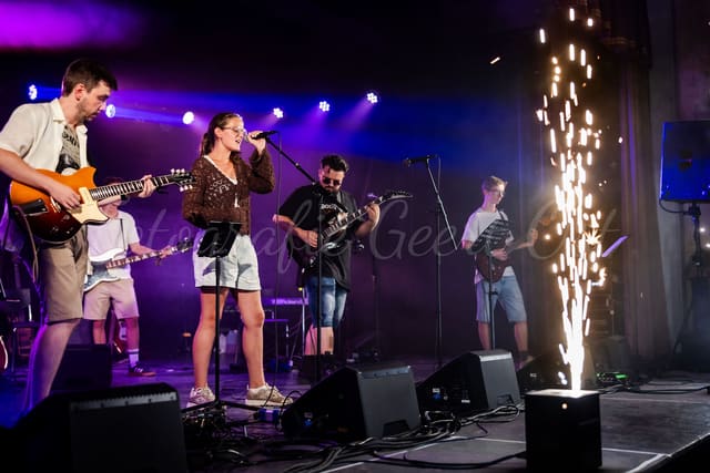 Band op het podium in paars en blauw licht met een vonkenfontein ernaast