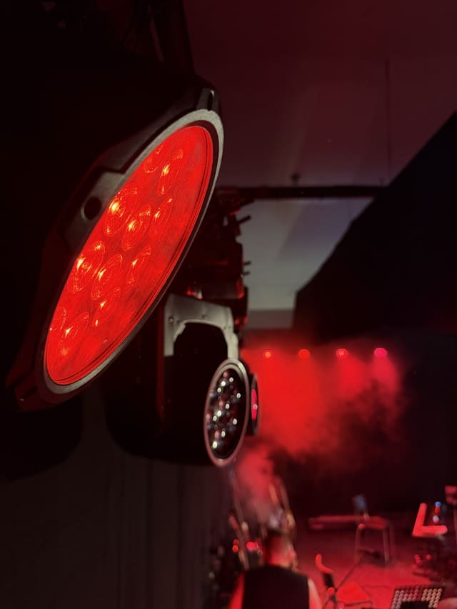 Close-up van een rood oplichtende LED-wash, op de achtergrond rode beams in de haze