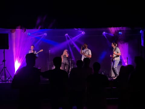 Band op een podium in paars en blauw licht met publiek ervoor